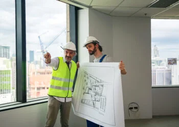 Profesionales de SIAGT revisando planos arquitectónicos con un fondo de un proyecto en desarrollo.